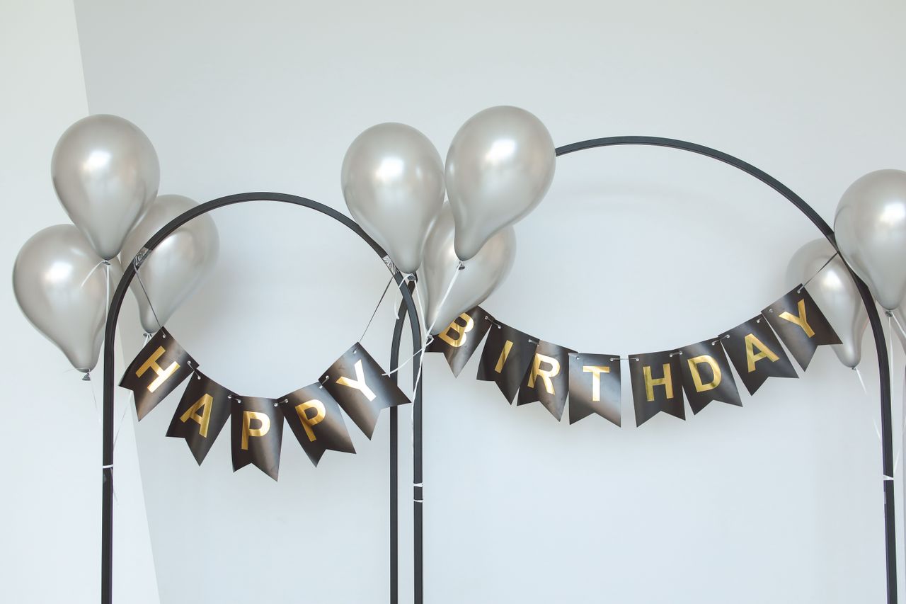 Stylish birthday party decor with silver balloons and black-gold banner.