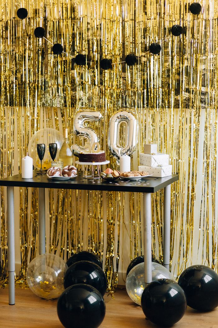 A stylish setup for a 50th birthday party featuring golden decorations and a festive cake.