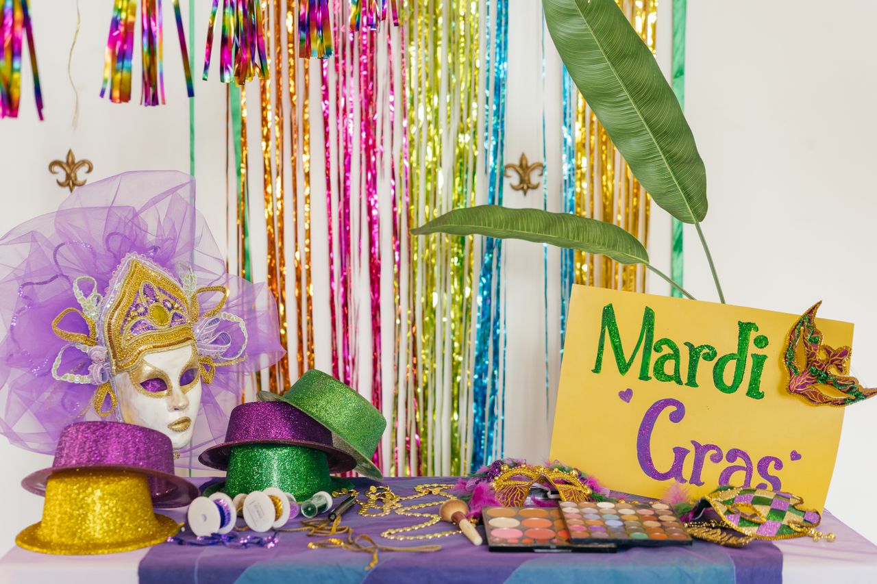 Colorful Mardi Gras setup with masks, hats, and makeup brushes creating a festive atmosphere.